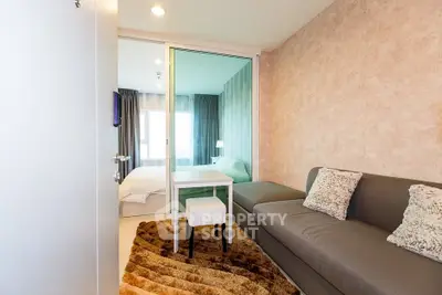 Modern apartment with cozy living area and stylish bedroom separated by glass wall.