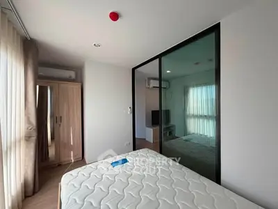 Modern bedroom with large window and mirrored wardrobe in stylish apartment.
