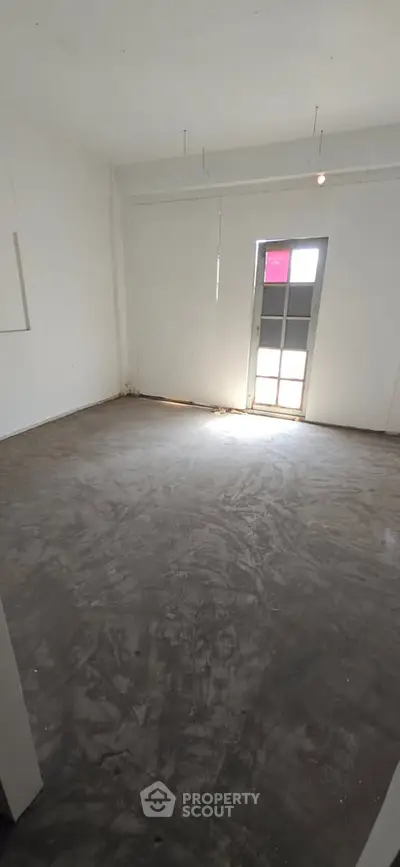 Spacious empty room with concrete floor and natural light from window, ideal for customization.