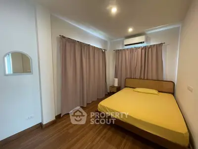 Cozy bedroom with wooden flooring and air conditioning, featuring a comfortable bed and soft lighting.