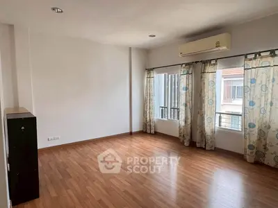 Spacious empty room with wooden flooring and large windows, perfect for customization.