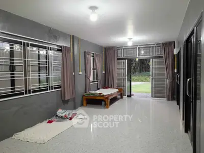 Spacious living room with large windows and garden view, featuring minimalist decor and natural light.