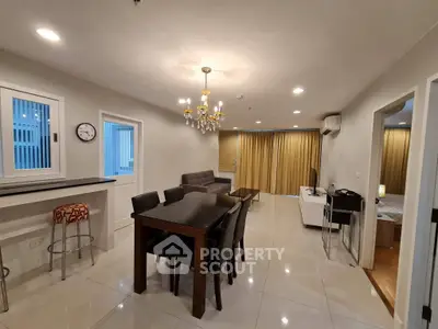 Spacious modern living room with elegant chandelier and open dining area in a stylish apartment.