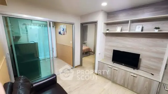 Modern living room with sleek TV unit and sliding glass doors leading to a cozy bedroom.