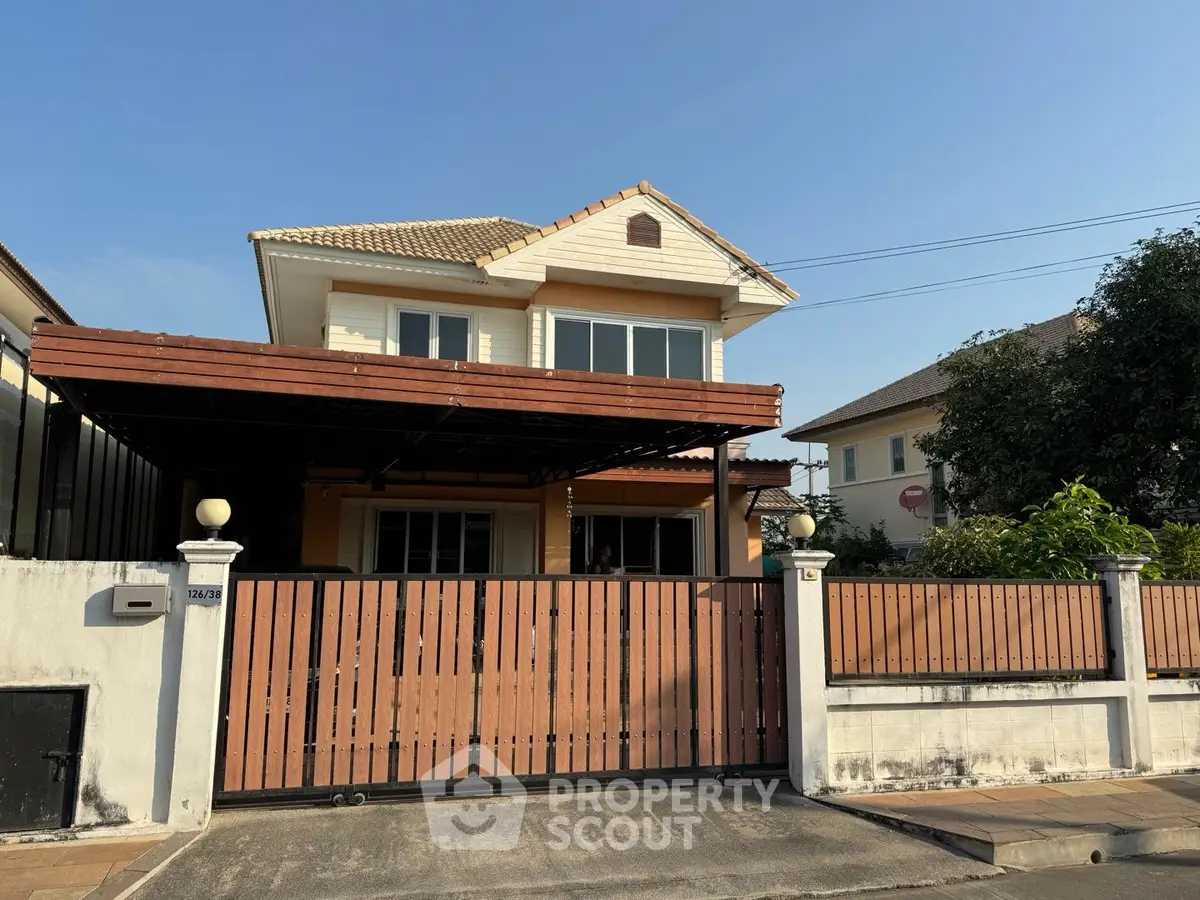 Charming two-story house with a gated wooden fence and spacious front yard.