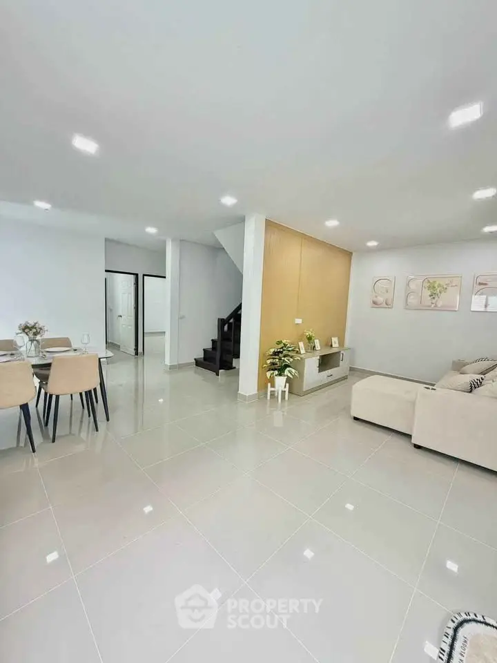 Spacious modern living room with elegant dining area and staircase in open layout.