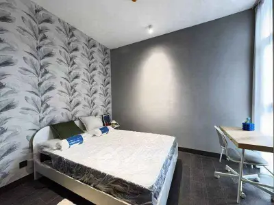 Modern bedroom with stylish wallpaper and natural light, featuring a cozy bed and a functional study desk.