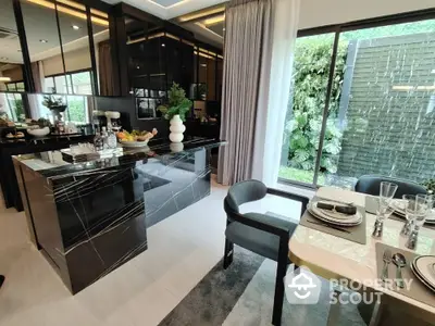 Luxurious modern kitchen with sleek black marble island and elegant dining area overlooking lush garden.