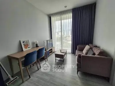 Modern living room with stylish furniture and large window offering natural light.