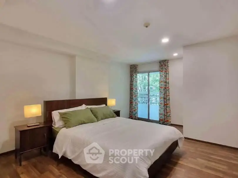 Spacious bedroom with balcony access and elegant decor in modern apartment.