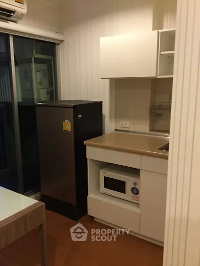 Compact kitchen with modern appliances and sleek cabinetry in cozy apartment.