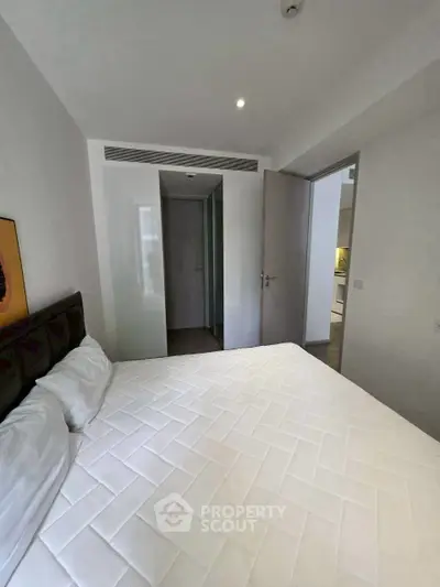Modern bedroom with minimalist design and white bedding in a contemporary apartment.