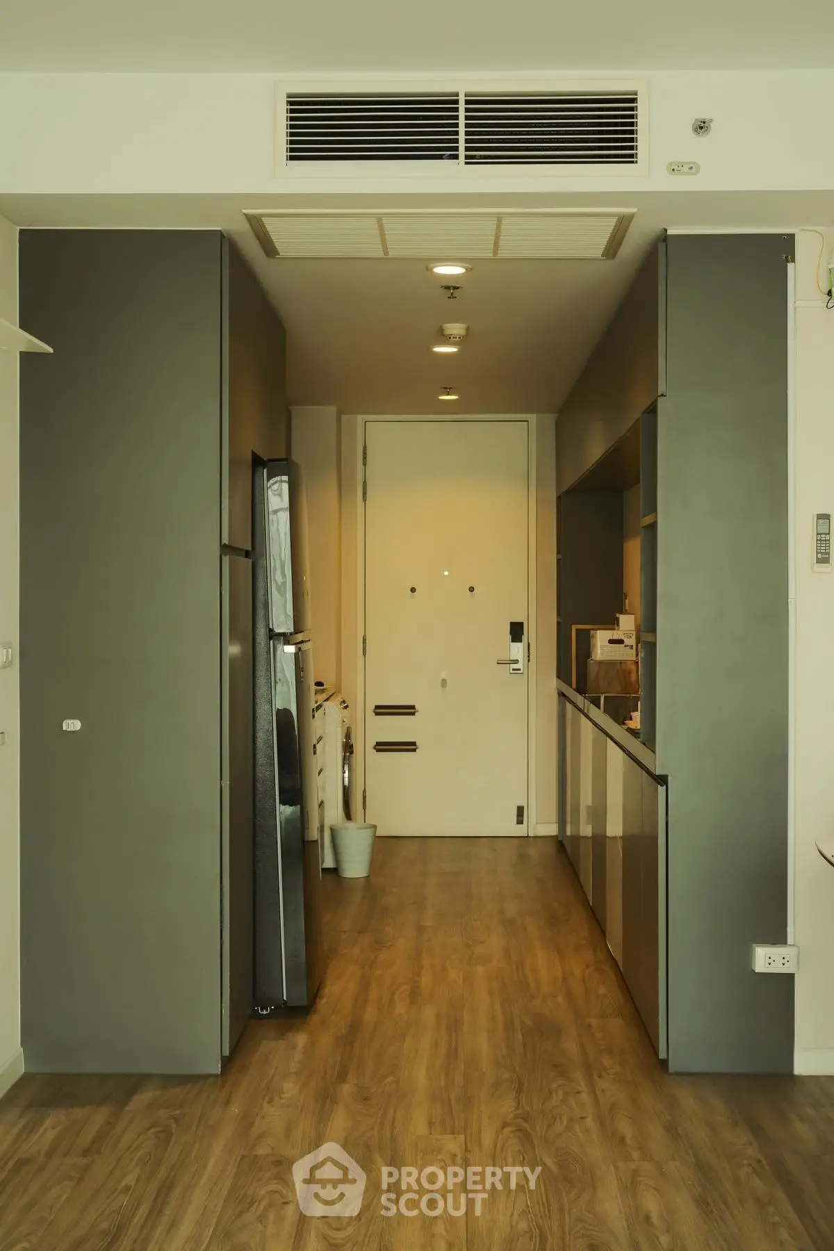 Modern apartment hallway with sleek kitchen and wooden flooring