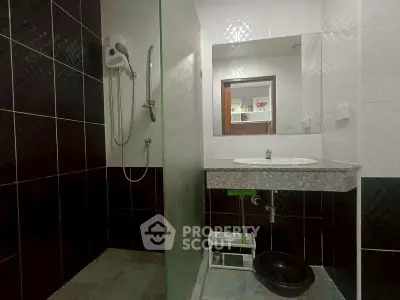 Modern bathroom with sleek black and white tiles, glass shower, and stylish vanity.