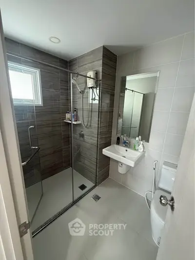 Modern bathroom with glass shower and sleek fixtures in contemporary home.