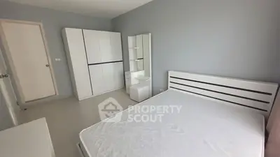 Modern minimalist bedroom with sleek white furniture and ample natural light.