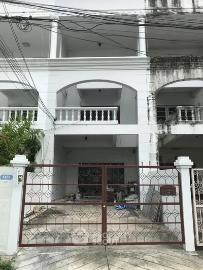Spacious multi-story white townhouse with gated entrance and balcony