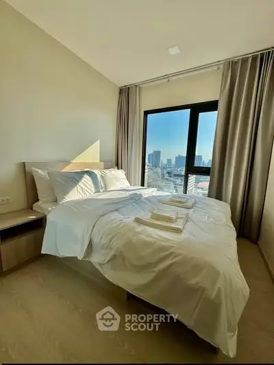 Modern bedroom with city view and natural light, featuring cozy bed and elegant curtains.