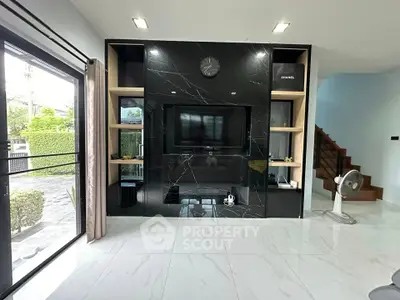 Modern living room with sleek black marble TV wall and large windows for natural light.