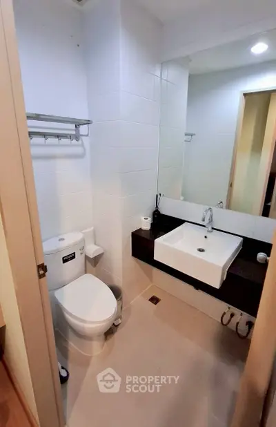 Modern bathroom with sleek fixtures and large mirror in contemporary apartment.