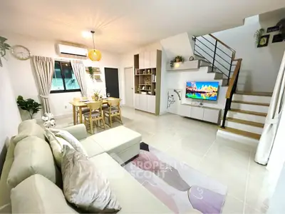 Modern living room with stylish decor, open layout, and staircase leading to upper floor.