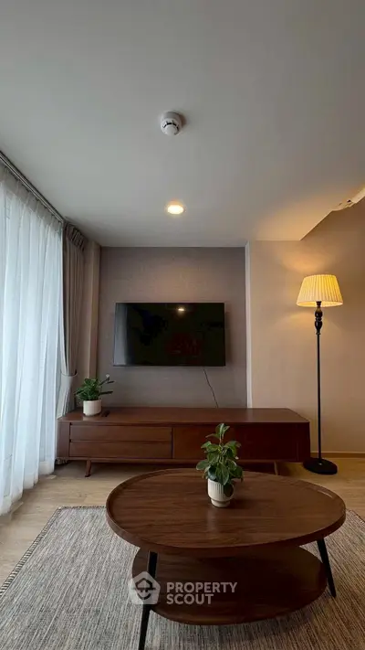 Modern living room with stylish furniture and wall-mounted TV, featuring elegant decor and natural light.