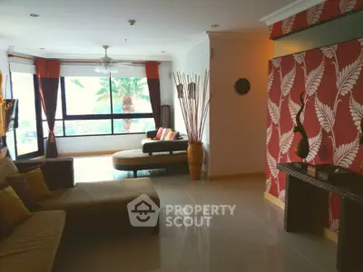 Spacious living room with stylish decor and large windows offering natural light and a cozy seating area.