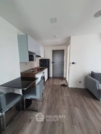 Modern apartment interior with sleek kitchen and cozy living area, featuring contemporary furniture and appliances.