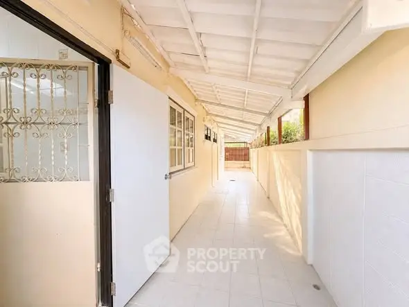 Bright corridor with tiled flooring and open access to outdoor area, perfect for ventilation and natural light.