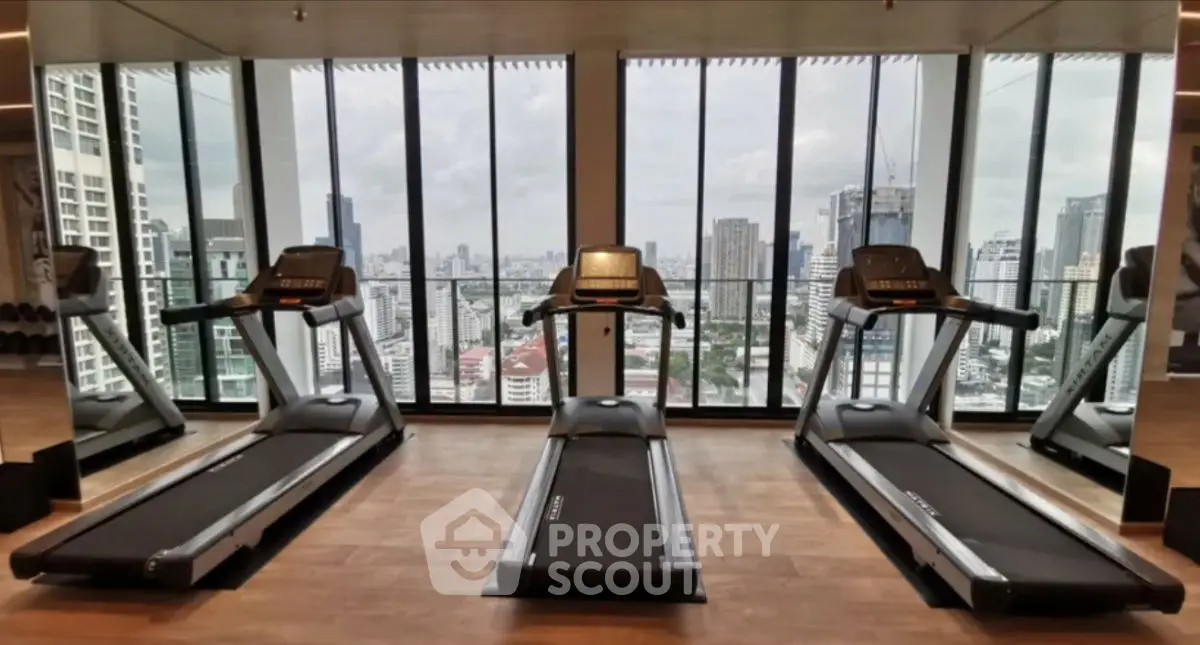 Modern gym with city view featuring treadmills and floor-to-ceiling windows.