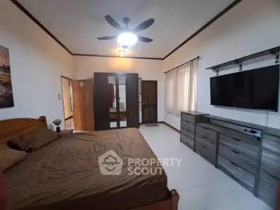 Spacious bedroom with modern furnishings and large TV in a cozy home.