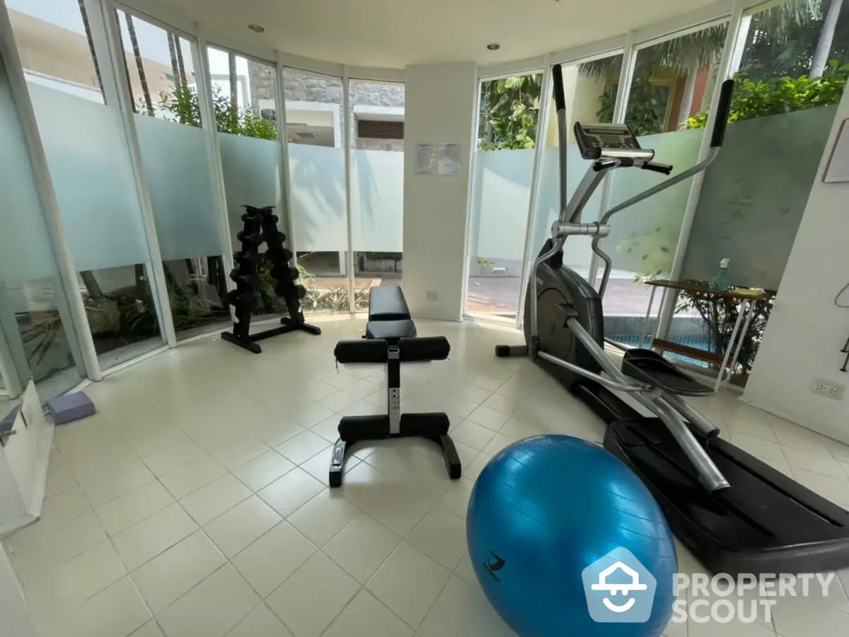 Modern home gym with treadmill, weights, and exercise ball in bright room