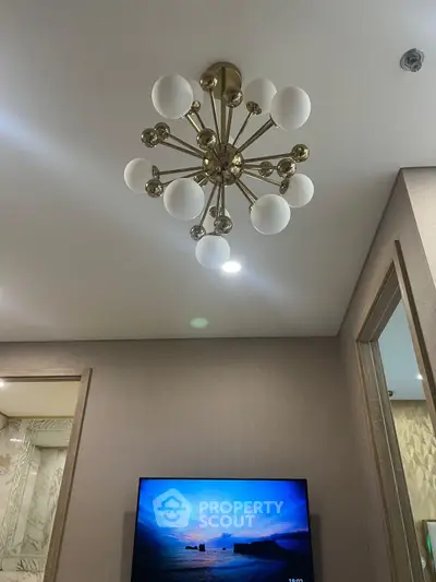 Modern living room with stylish chandelier and wall-mounted TV