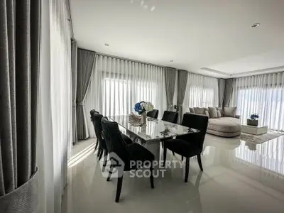 Luxurious living room with elegant dining area and plush seating, featuring floor-to-ceiling windows and modern decor.
