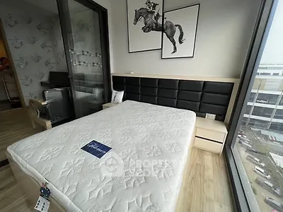 Modern bedroom with large windows and stylish decor, featuring a comfortable bed and elegant artwork.