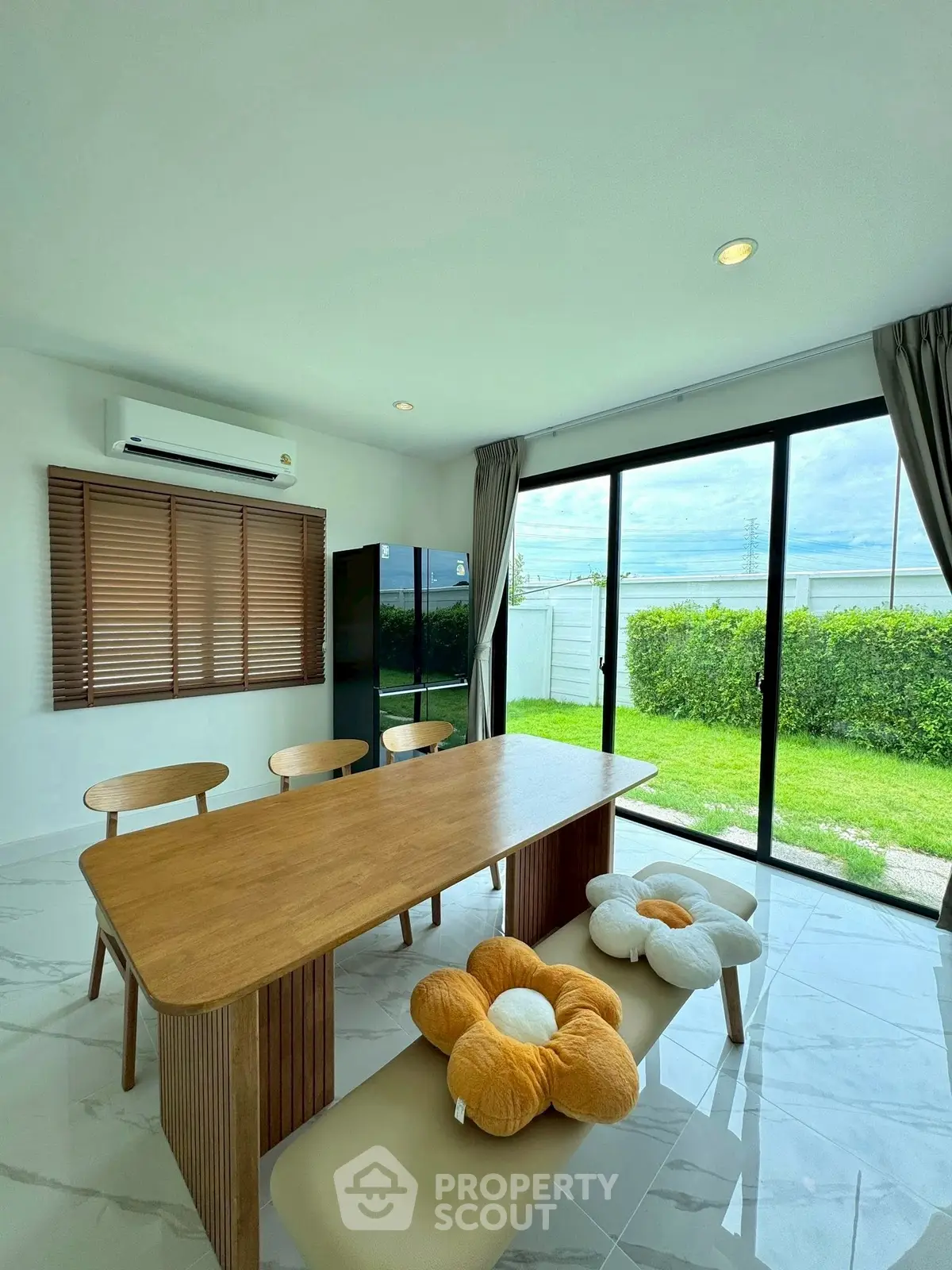 Modern dining area with garden view, featuring stylish wooden table and chairs, and large glass doors.