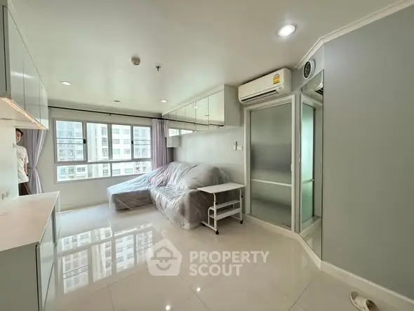 Modern living room with large windows and sleek furnishings in a high-rise apartment.