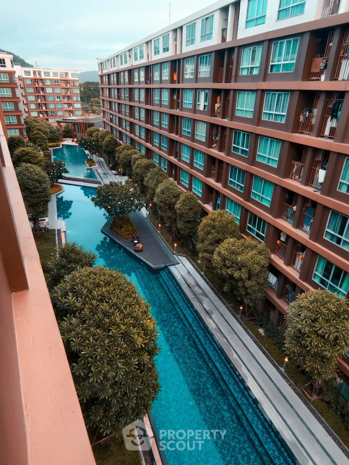 Stunning view of modern apartment complex with lush greenery and inviting swimming pool.