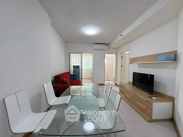 Modern living room with glass dining table and red sofa in a bright apartment.