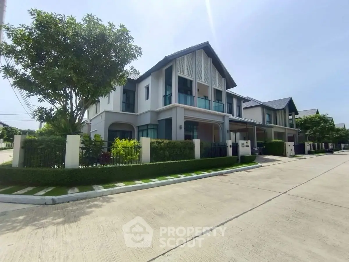 Modern two-story house with sleek design and lush greenery in a serene neighborhood.