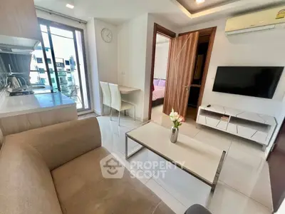 Modern living room with open kitchen and balcony view in stylish apartment.