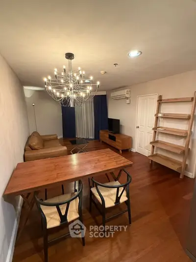 Stylish living room with modern chandelier, wooden furniture, and cozy seating area.