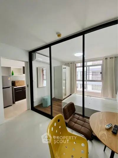 Modern apartment interior with glass partition, stylish furniture, and natural light.