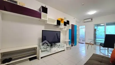 Modern living room with sleek shelving and large TV in a stylish apartment.