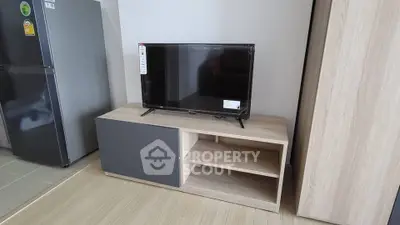 Modern living room with sleek TV stand and flat-screen TV, adjacent to a stylish kitchen area.