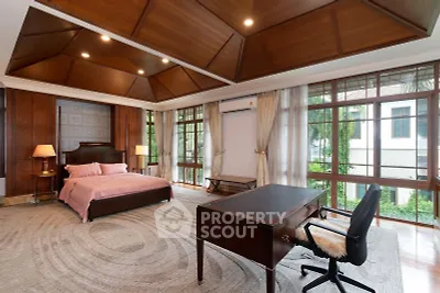 Luxurious bedroom with elegant wooden ceiling and large windows offering a serene garden view.