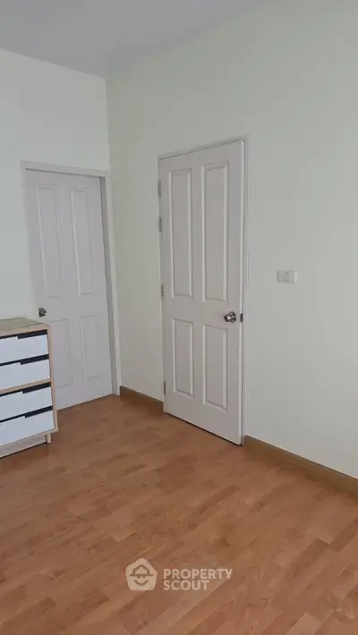 Minimalist bedroom with wooden flooring and white doors
