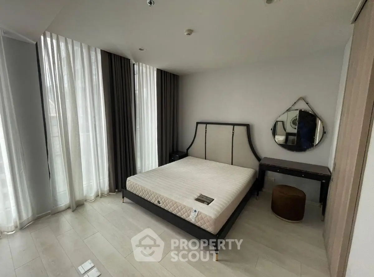 Spacious bedroom with elegant decor and large windows for natural light