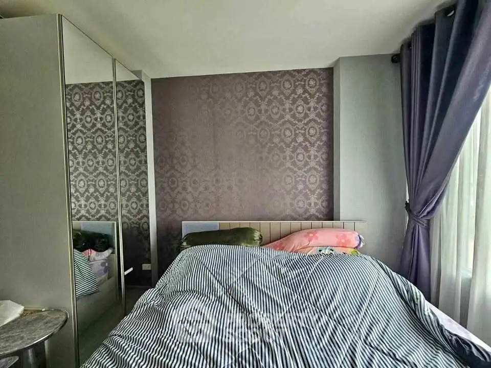 Cozy bedroom with stylish wallpaper and mirrored wardrobe, perfect for modern living.