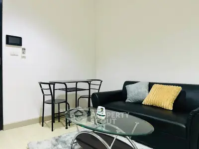 Modern living room with sleek black sofa, glass coffee table, and cozy dining area.